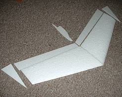 Das Bild zeigt einen Micro Zicky Bausatz. Dabei handelt es sich um einen kleinen Nurflügler. Der Bausatz besteht aus 2 Flächenhälften, den Winglets, den Rudern und der Wurfkufe.